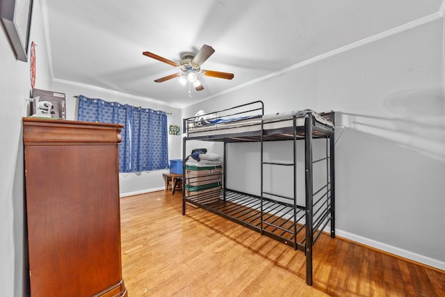 bedroom featuring ceiling fan, baseboards, crown molding, and wood finished floors