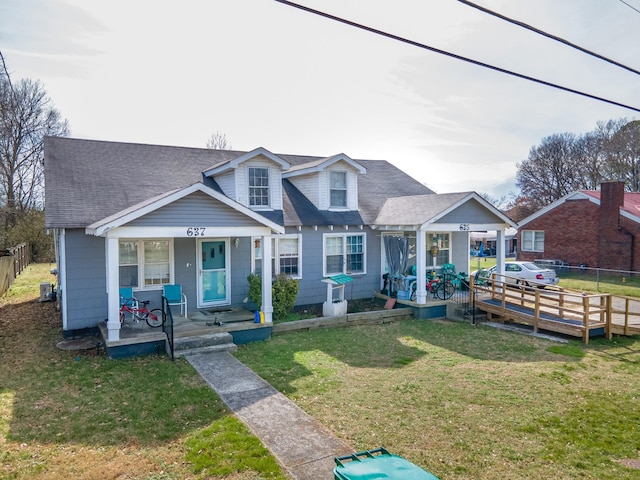 view of front of house featuring a shingled roof, fence, a front lawn, and a porch