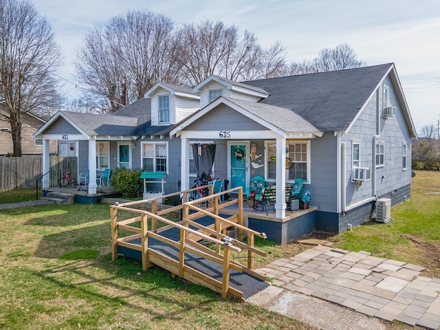 view of front facade featuring a porch, cooling unit, a shingled roof, and a front lawn