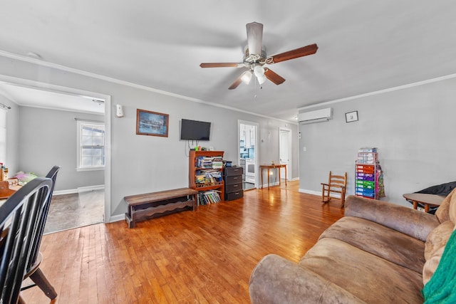 living area with a wall unit AC, light wood-type flooring, baseboards, and crown molding