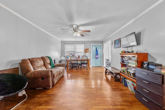 living room featuring a ceiling fan, ornamental molding, and wood finished floors