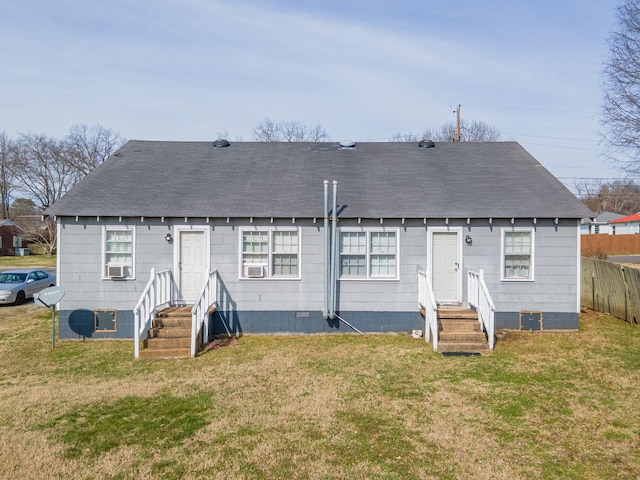 back of house with entry steps, roof with shingles, and a lawn