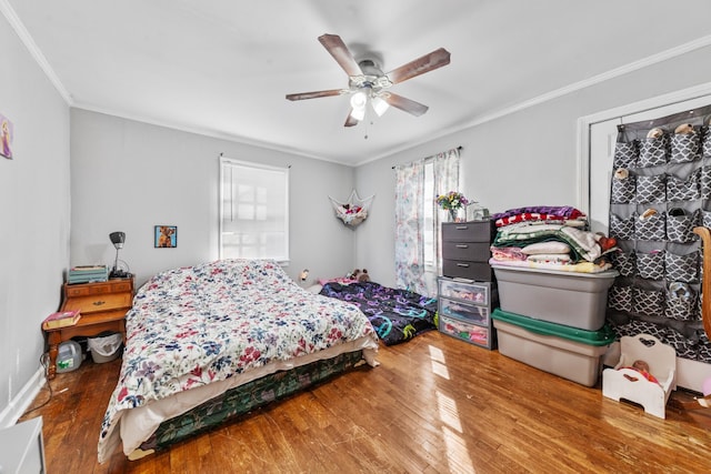 bedroom with a ceiling fan, ornamental molding, and wood finished floors