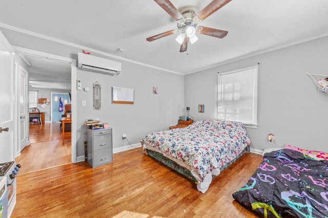 bedroom with an AC wall unit, ornamental molding, wood finished floors, and baseboards