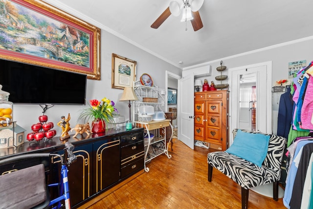 living area featuring a ceiling fan, light wood-type flooring, and crown molding