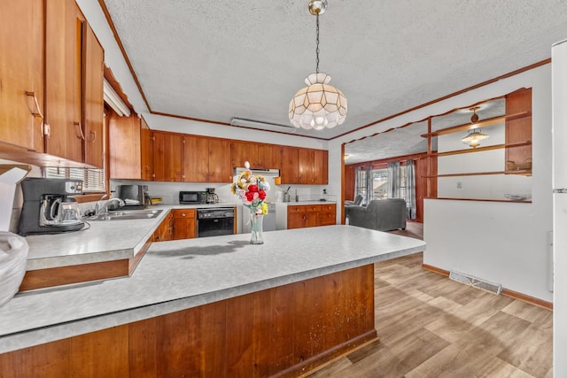 kitchen with visible vents, brown cabinetry, decorative light fixtures, light countertops, and a sink