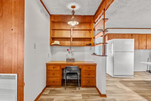 unfurnished office featuring a textured ceiling, visible vents, baseboards, ornamental molding, and light wood finished floors