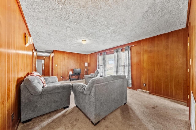 living area featuring wooden walls, visible vents, light carpet, and a textured ceiling