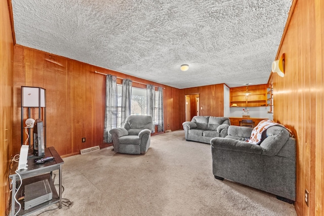 carpeted living room featuring visible vents, wooden walls, and a textured ceiling