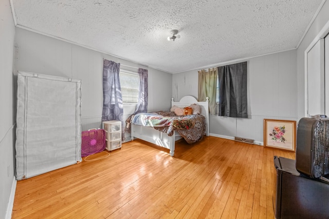 bedroom with crown molding, a textured ceiling, and wood finished floors