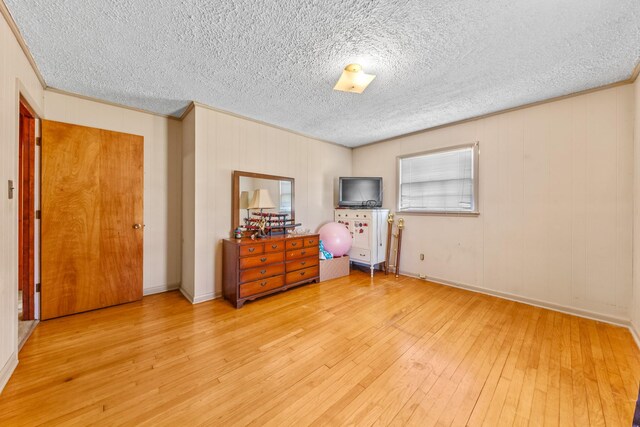 bedroom with crown molding, a textured ceiling, baseboards, and light wood-style floors