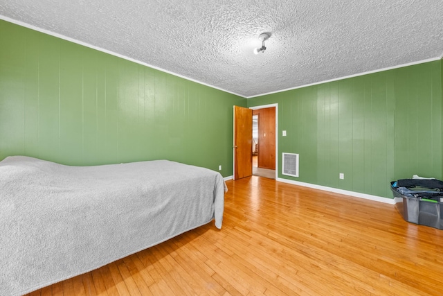 bedroom with ornamental molding, visible vents, and wood finished floors