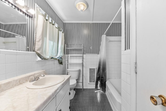 bathroom featuring toilet, tile patterned flooring, shower / bath combo with shower curtain, vanity, and tile walls