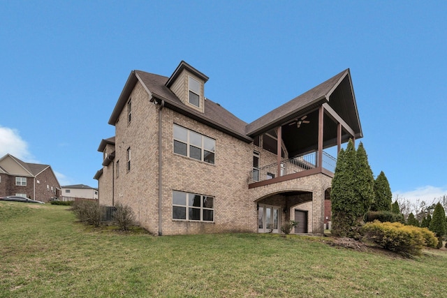 back of property with brick siding, a lawn, a balcony, and a ceiling fan