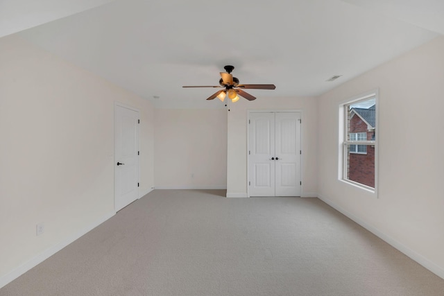 interior space featuring visible vents, baseboards, a ceiling fan, and light colored carpet