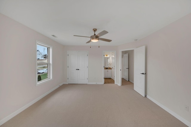 unfurnished bedroom with visible vents, baseboards, a ceiling fan, light colored carpet, and ensuite bathroom