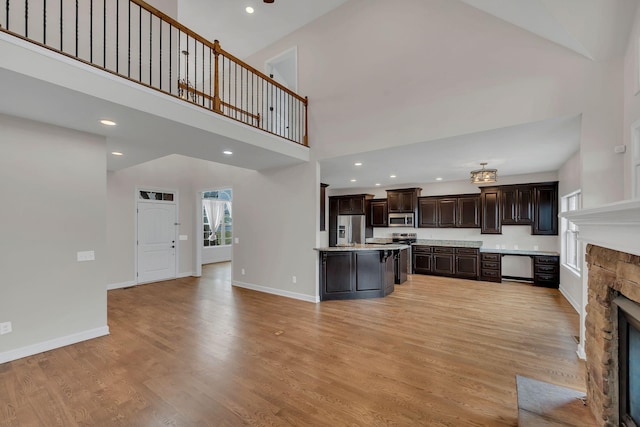 kitchen with a center island, stainless steel appliances, light countertops, open floor plan, and dark brown cabinetry