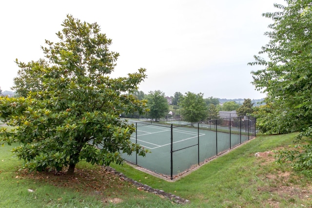 view of tennis court featuring a yard and fence