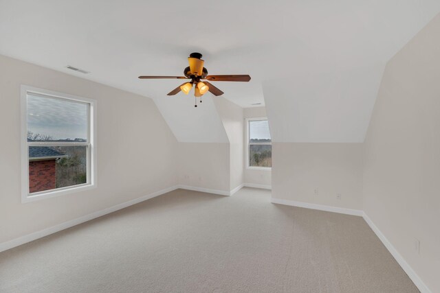 additional living space featuring ceiling fan, light carpet, visible vents, baseboards, and vaulted ceiling