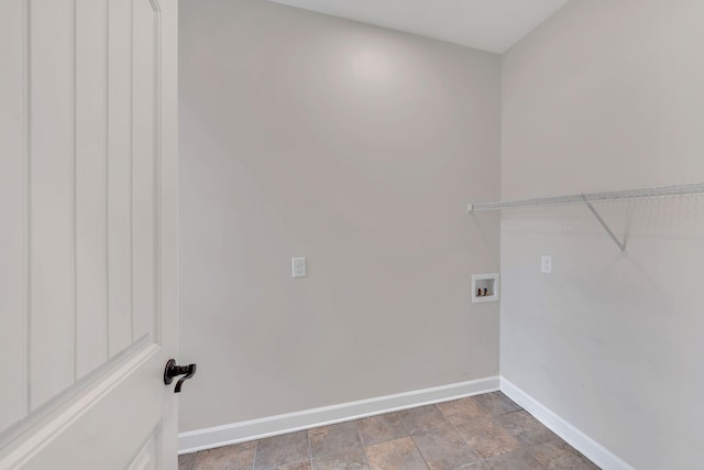 laundry area with laundry area, stone finish flooring, hookup for a washing machine, and baseboards