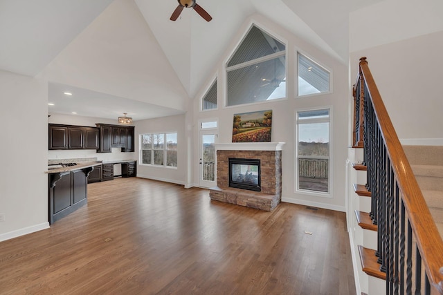 living room featuring stairs, a stone fireplace, a wealth of natural light, and light wood-style floors