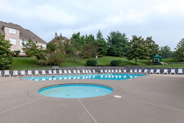 pool featuring a yard, playground community, a patio, and fence