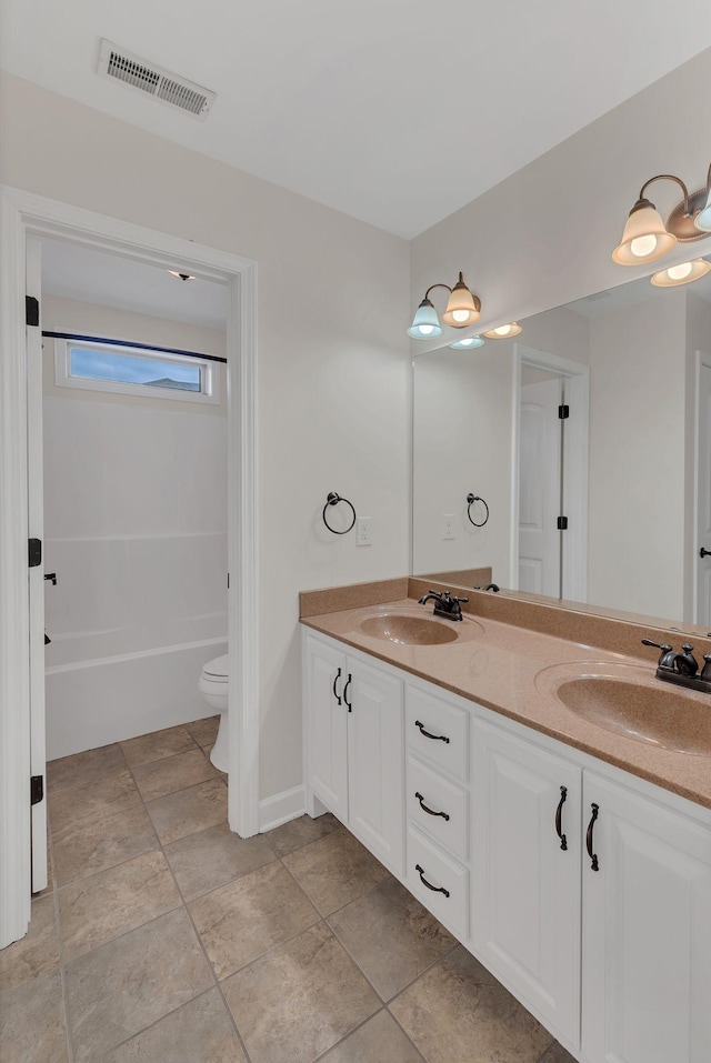 bathroom with toilet, double vanity, a sink, and visible vents