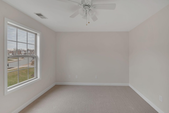 spare room featuring a wealth of natural light, baseboards, visible vents, and carpet flooring