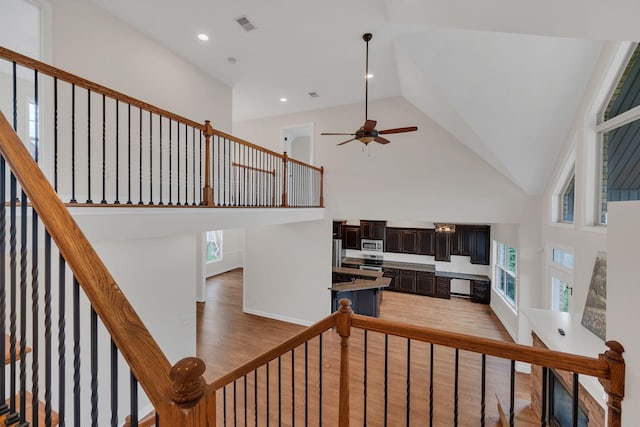 stairway featuring high vaulted ceiling, recessed lighting, wood finished floors, a ceiling fan, and visible vents