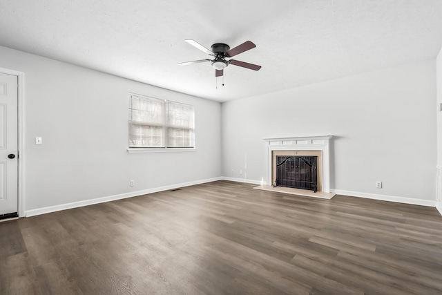 unfurnished living room with a ceiling fan, dark wood-style flooring, a fireplace, and baseboards