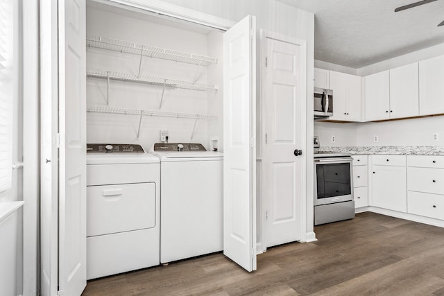 clothes washing area with a textured ceiling, laundry area, wood finished floors, and washing machine and clothes dryer