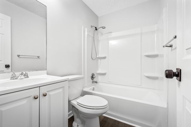 full bathroom featuring toilet, wood finished floors, bathtub / shower combination, a textured ceiling, and vanity