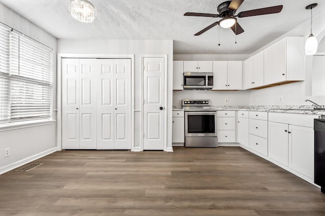 kitchen featuring light countertops, appliances with stainless steel finishes, hanging light fixtures, and white cabinets