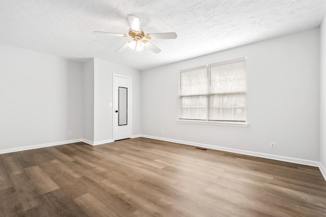 unfurnished room featuring a textured ceiling, dark wood-type flooring, and baseboards