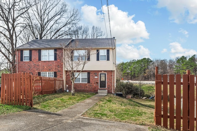 view of front facade with a fenced front yard, a front yard, and brick siding