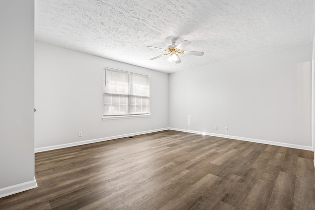 empty room with dark wood-style floors, a textured ceiling, baseboards, and a ceiling fan