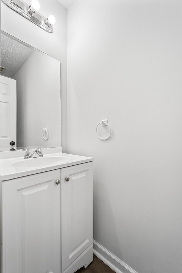 bathroom featuring visible vents, baseboards, a textured ceiling, and vanity