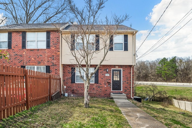 view of front facade with entry steps, brick siding, a front yard, and fence private yard