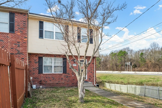 colonial-style house with a front yard, brick siding, and fence