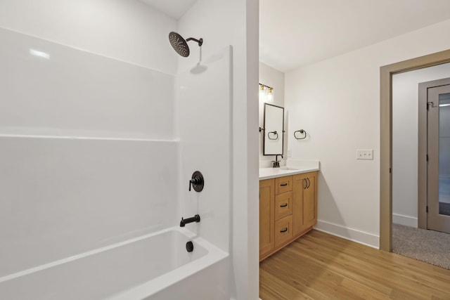 bathroom featuring shower / bathtub combination, baseboards, wood finished floors, and vanity