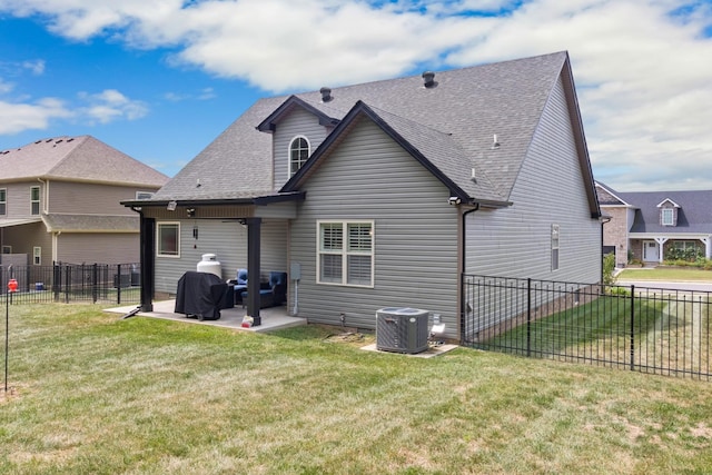 rear view of house featuring cooling unit, a patio area, a lawn, and roof with shingles