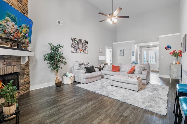 living area with a fireplace, dark wood finished floors, visible vents, and baseboards