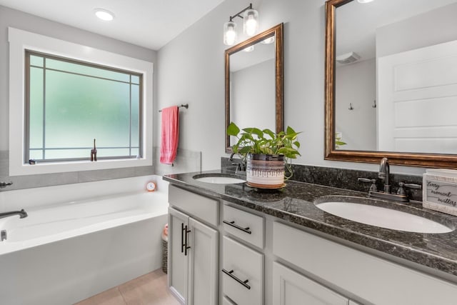 full bathroom featuring a garden tub, double vanity, tile patterned flooring, and a sink