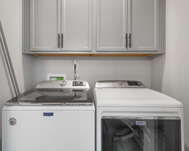 washroom featuring washing machine and dryer and cabinet space