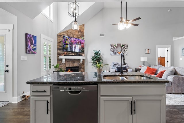 kitchen with a sink, dark stone counters, open floor plan, and stainless steel dishwasher