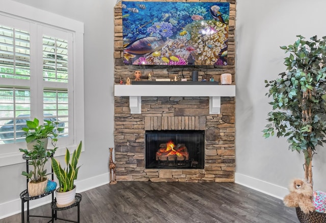 living room featuring baseboards, dark wood-type flooring, and a stone fireplace