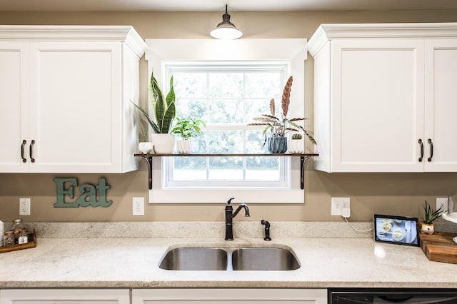 kitchen with black dishwasher, white cabinets, light stone counters, hanging light fixtures, and a sink