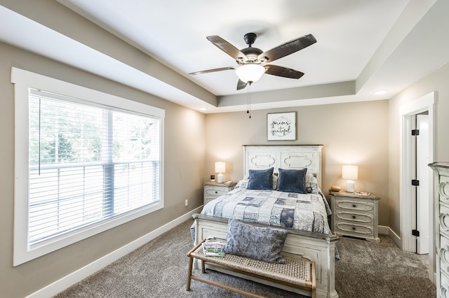 bedroom featuring ceiling fan, a tray ceiling, carpet flooring, and baseboards