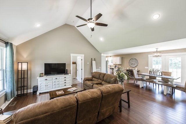 living area with high vaulted ceiling, visible vents, dark wood-type flooring, and ceiling fan with notable chandelier