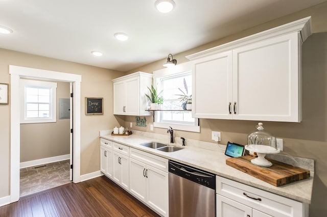 kitchen with dark wood-style floors, stainless steel dishwasher, white cabinets, a sink, and baseboards